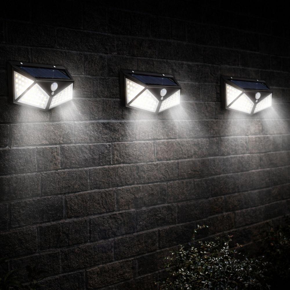 Quattro faretti da parete con pannello solare montati su muro di mattoni, accesi di notte in sequenza