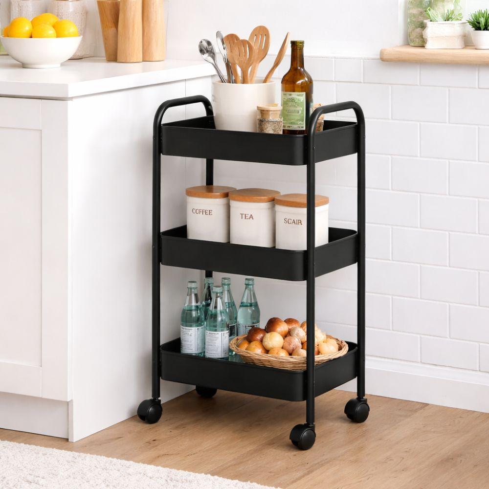 Carrello nero a tre ripiani in uso in cucina con bottiglie, arance e contenitori